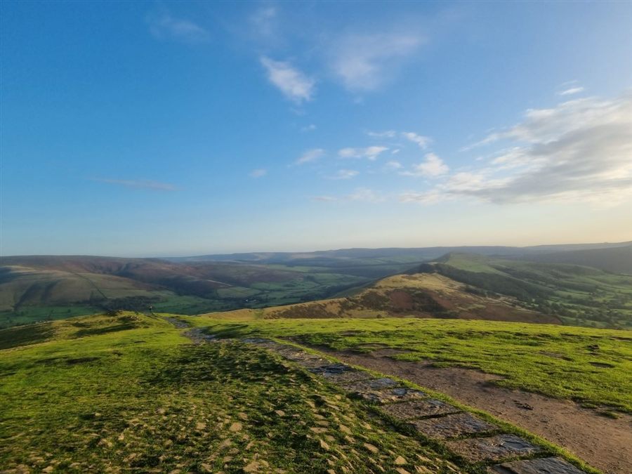 A stone path across green hills under a blue sky